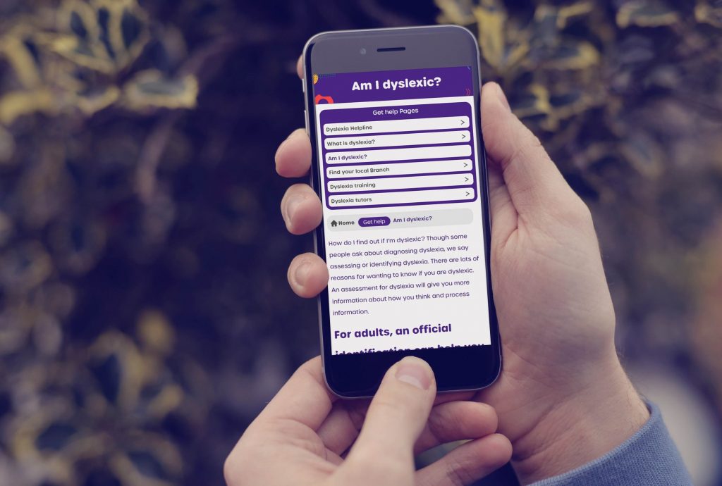 Mobile phone being held showing a web page 'Am I dyslexic'